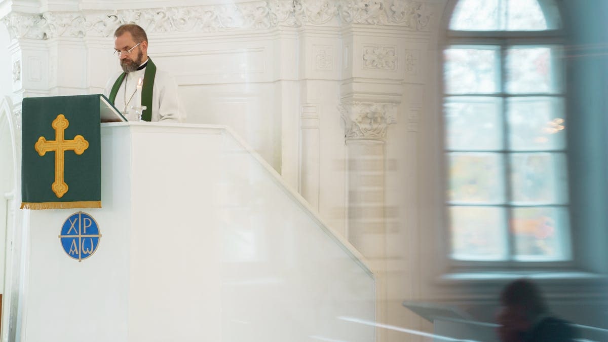 A preacher standing at a pulpit inside a historic church during a religious ceremony.